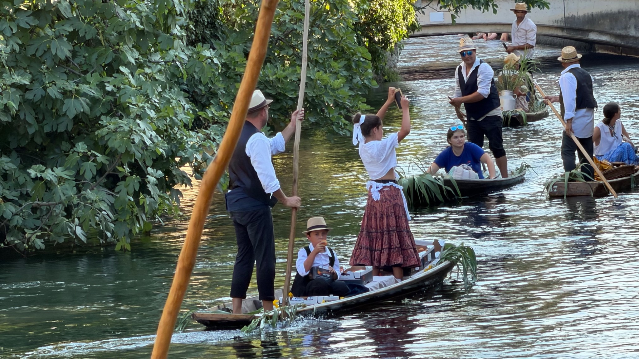 Traditioneel geklede deelnemers varen onder een brug door