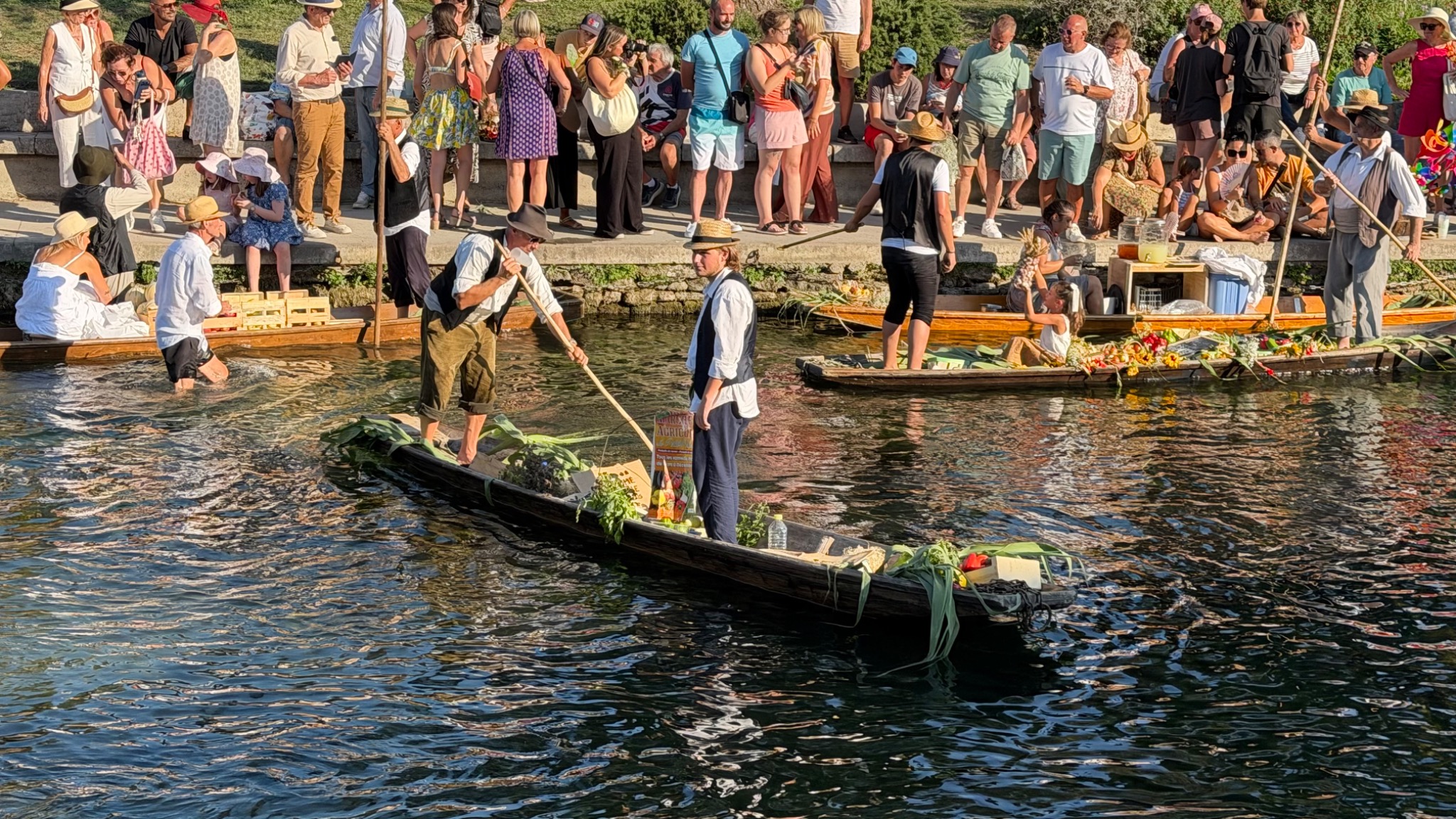 Een boot met verse producten vaart langs het publiek