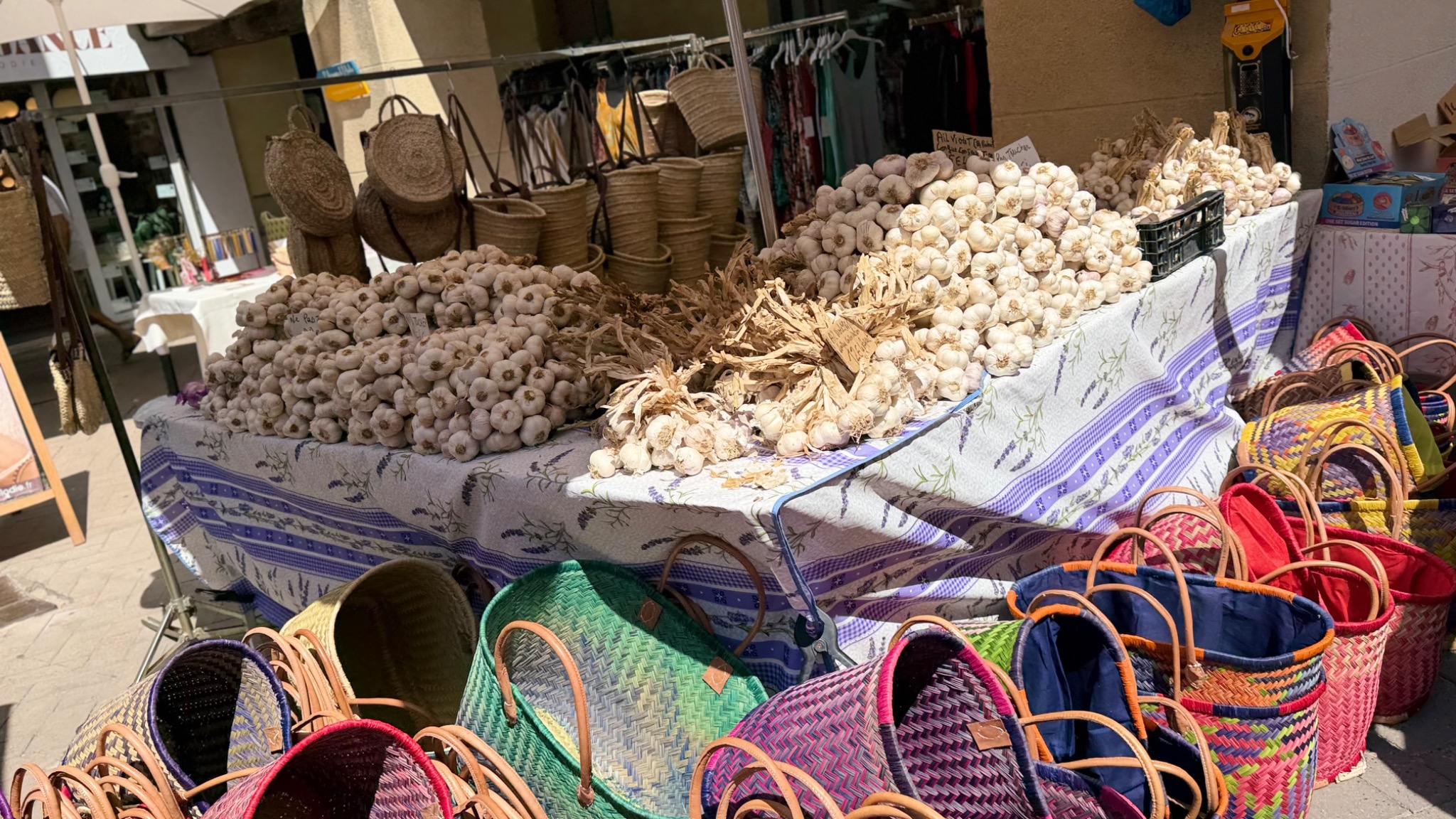 Kramen met verse knoflook en kleurrijke gevlochten manden op de zondagmarkt